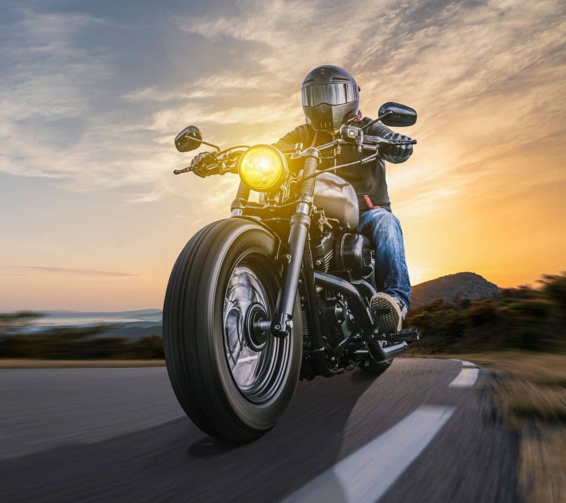 Man riding motorcycle on the highway with a nice sunset in the background,