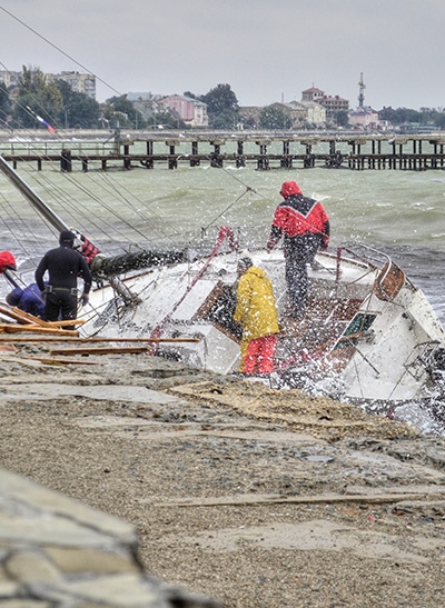 People working to save a wrecked sailboat.