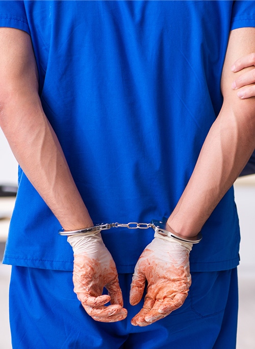 A doctor wearing medical gloves being handcuffed.